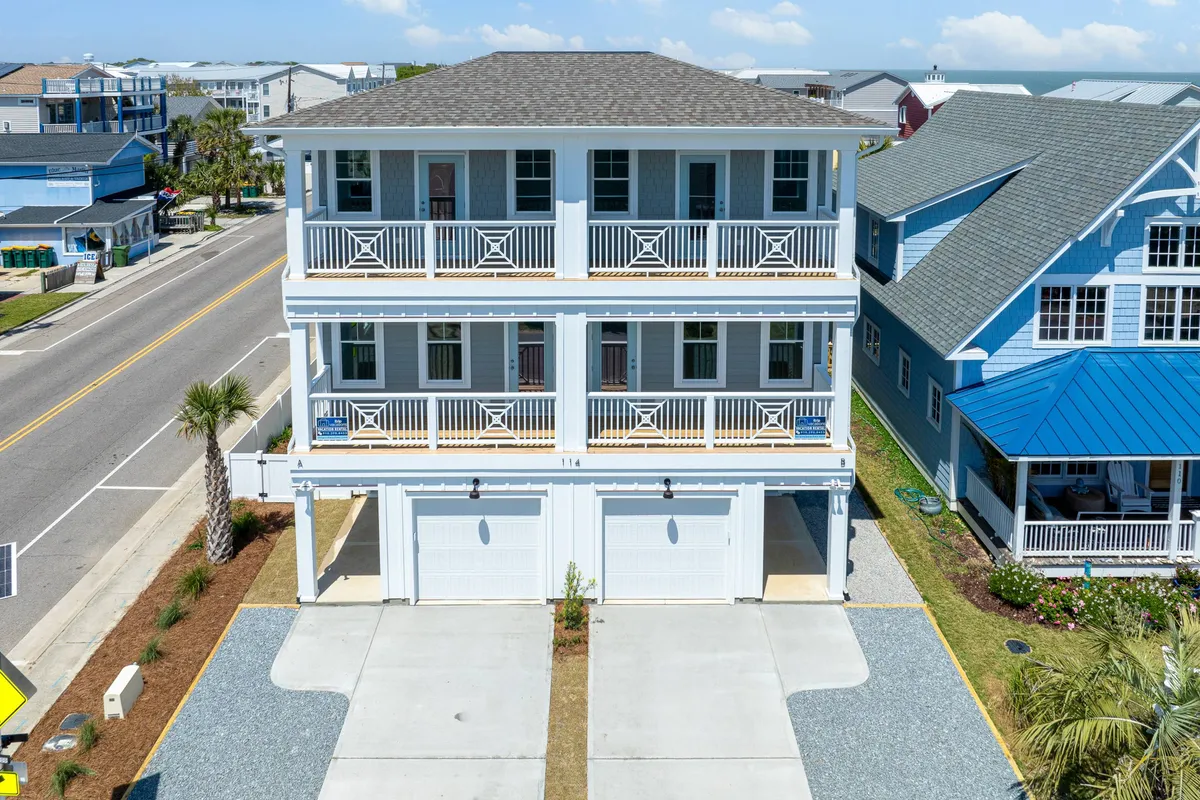 This cheerful exterior shot captures Doc's Beachwalk and neighboring houses, with prominent balconies, palm trees, and a welcoming driveway. The balconies hint at opportunities for outdoor relaxation and family gatherings, while the duplex structure is visible, supporting the narrative of accommodating large, multi-generational groups.