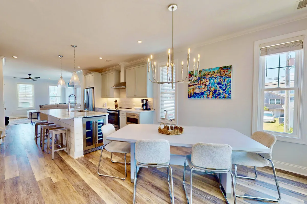 This image features a spacious kitchen island adjacent to a dining table, with artistic touches on the wall. The area is bright and open, allowing for seamless movement between cooking and dining activities. The inviting setup encourages family-style meals and social interaction.